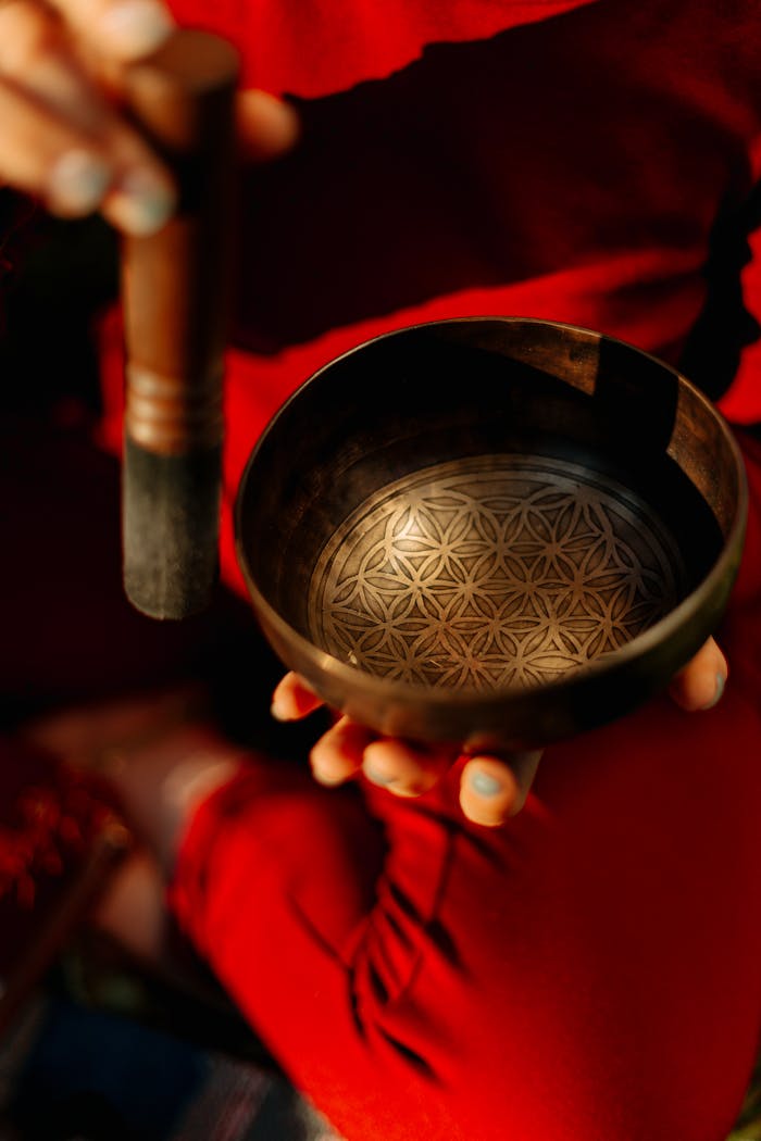 Close-up of hands holding a Tibetan singing bowl used in meditation and sound healing practices.